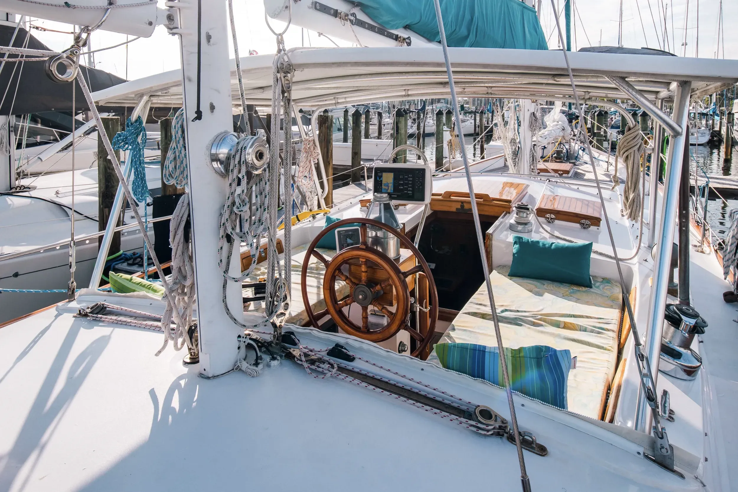 SV Cay Michele cockpit with wooden helm wheel, bimini top, and teak accents dockside in Gulfport, FL